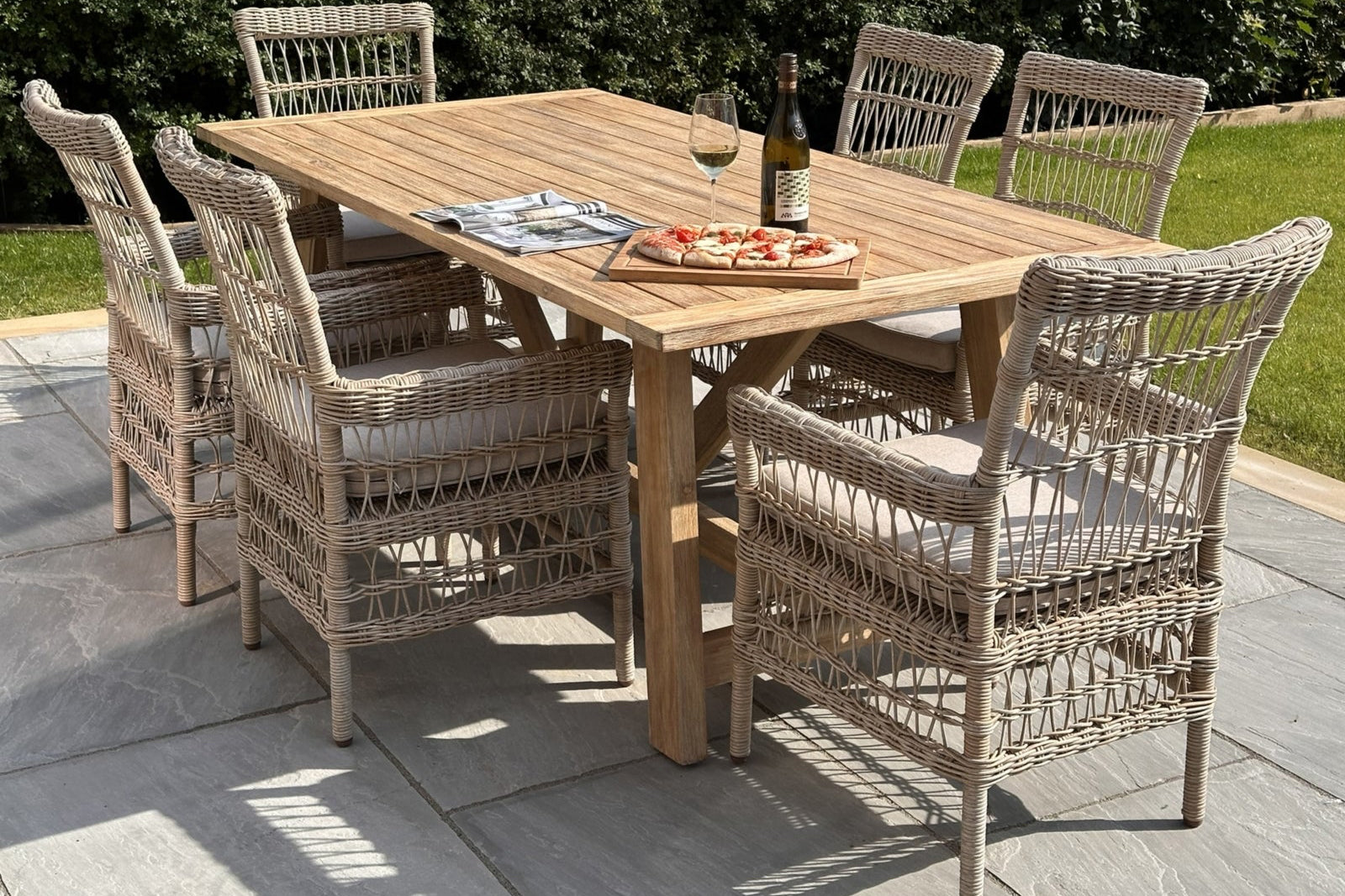 Outdoor dining setup with a wooden table and wicker chairs on a patio.