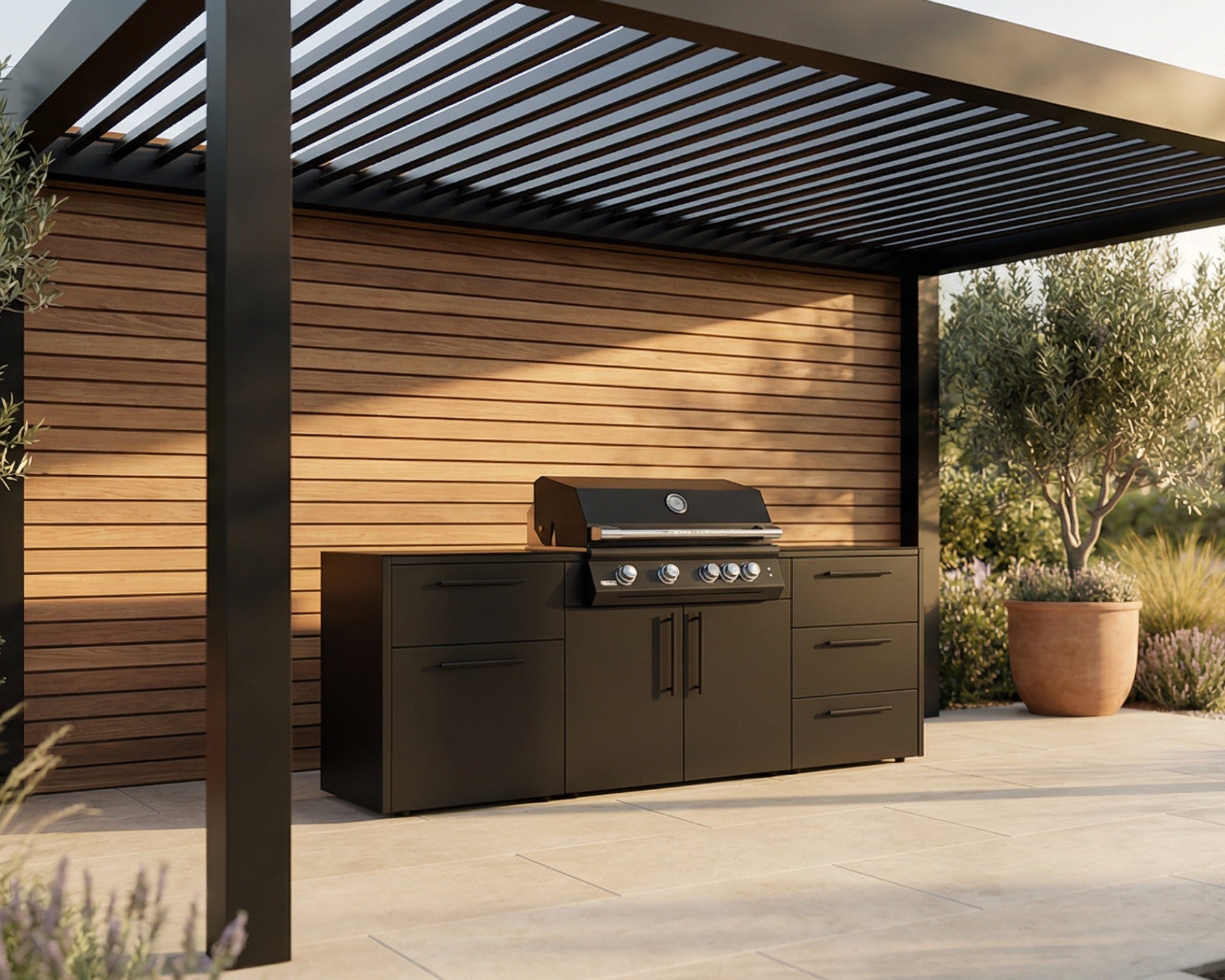 A black outdoor kitchen island set with a built-in gas grill, positioned under a modern black pergola with a wood-paneled wall and potted plants in the background.